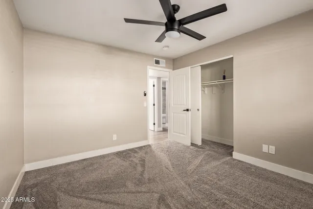 an empty room with closet and fan