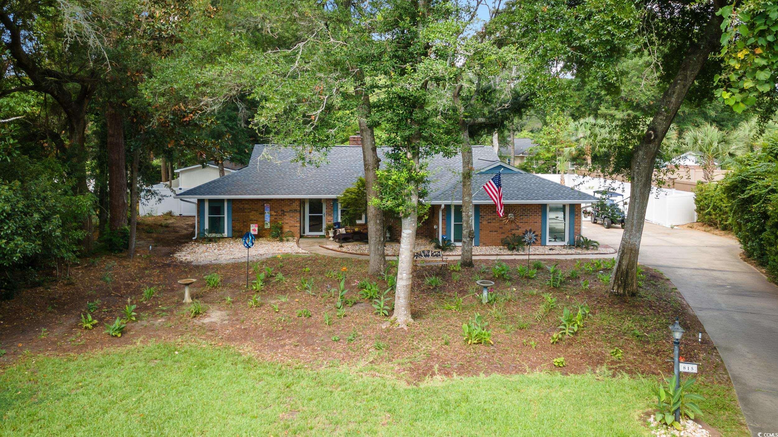 Ranch-style house with roof with shingles, concrete driveway, brick siding, and a front yard