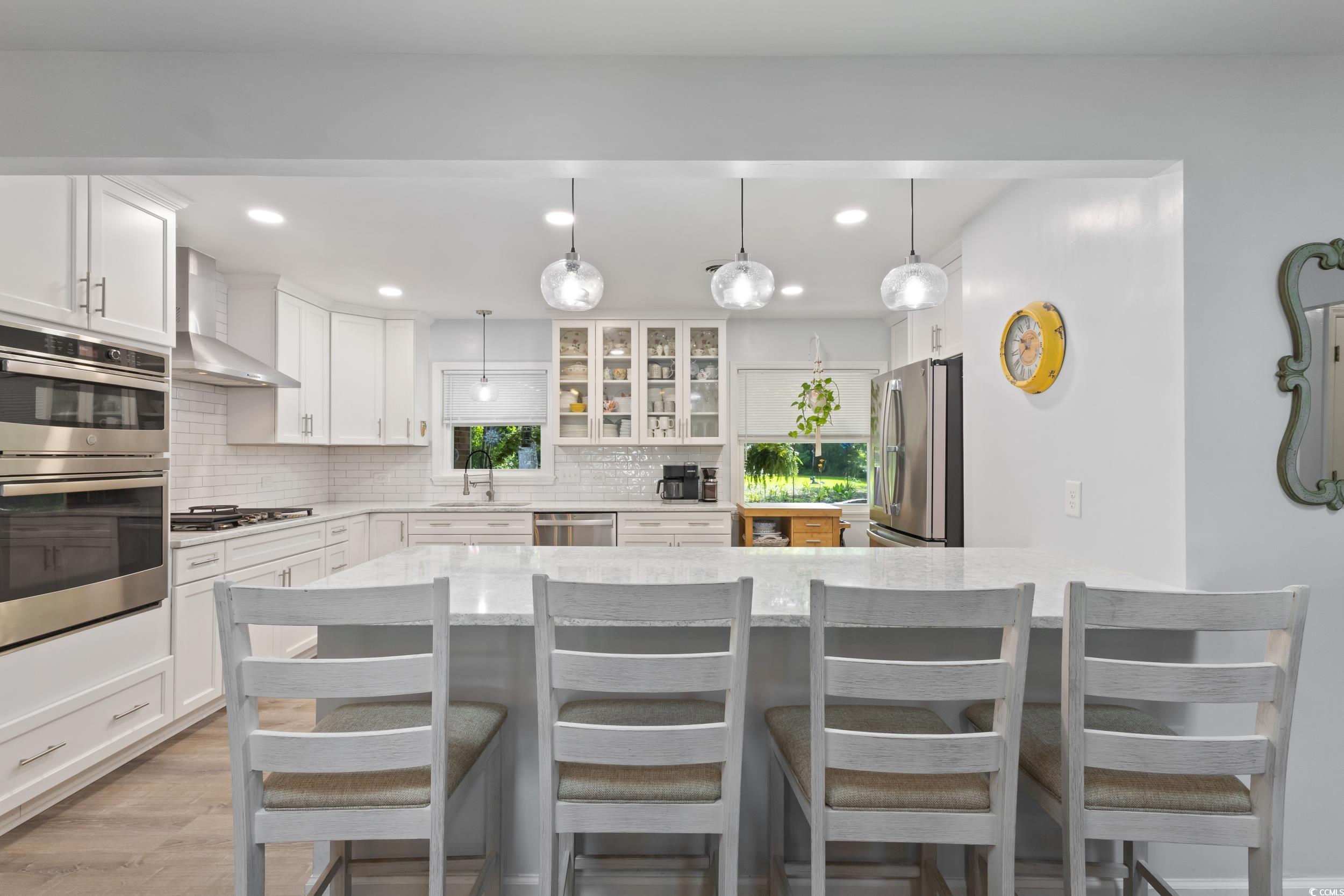 815 Tillson Road North Myrtle Beach, SC 29582 - Photo 11 of 39 Kitchen with wall chimney exhaust hood, recessed lighting, stainless steel appliances, light stone counters, and white cabinetry