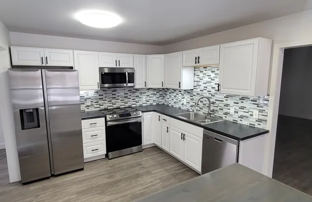 a kitchen with stainless steel appliances kitchen island granite countertop a refrigerator and a stove top oven