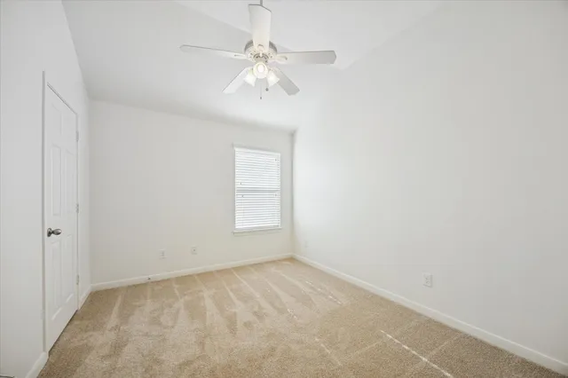 an empty room with a chandelier fan and windows