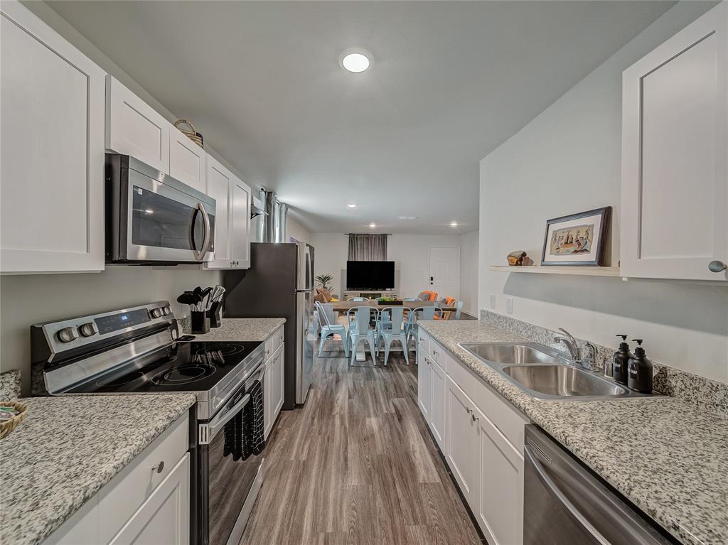 921 West 9th Street Bonham, TX 75418 - Photo 22 of 22 Kitchen with stainless steel appliances, white cabinetry, dark wood-type flooring, open floor plan, and light stone countertops