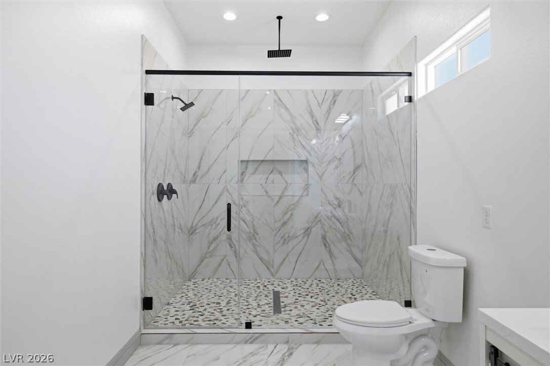 1061 Factory Road Pahrump, NV 89048 - Photo 27 of 41 Modern bathroom boasts a spacious glass-enclosed shower with luxurious marble-patterned tile and a pebble floor.