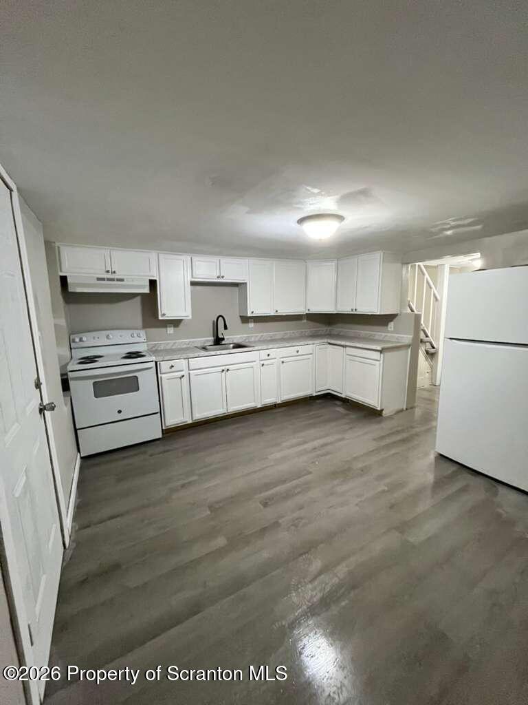 a large kitchen with stainless steel appliances wooden floor and a refrigerator