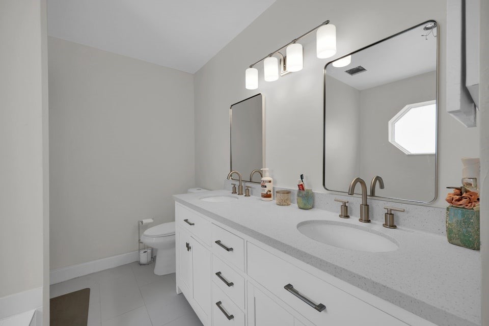 1950 Southwest Logwood Road Port St. Lucie, FL 34953 - Photo 15 of 32 a bathroom with a double vanity sink mirror and toilet