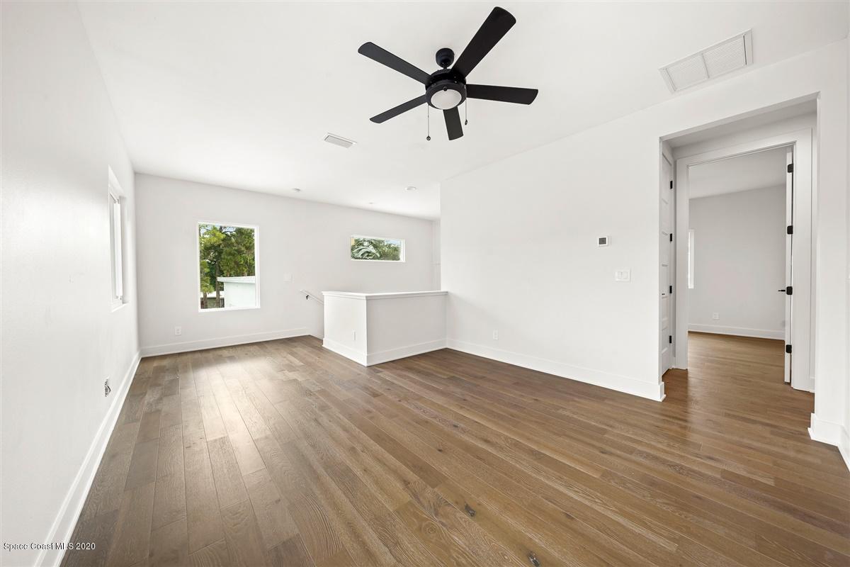 2138 Country Club Road Melbourne, FL 32901 - Photo 39 of 92 an empty room with wooden floor a ceiling fan and windows