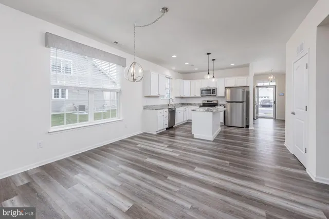 a kitchen with stainless steel appliances granite countertop a sink cabinets and wooden floor