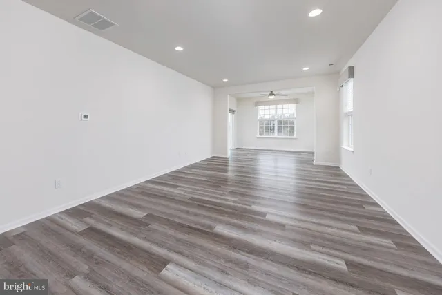 a view of empty room with wooden floor and windows