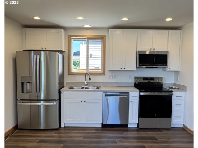 a kitchen with stainless steel appliances granite countertop a stove a refrigerator a sink and a microwave