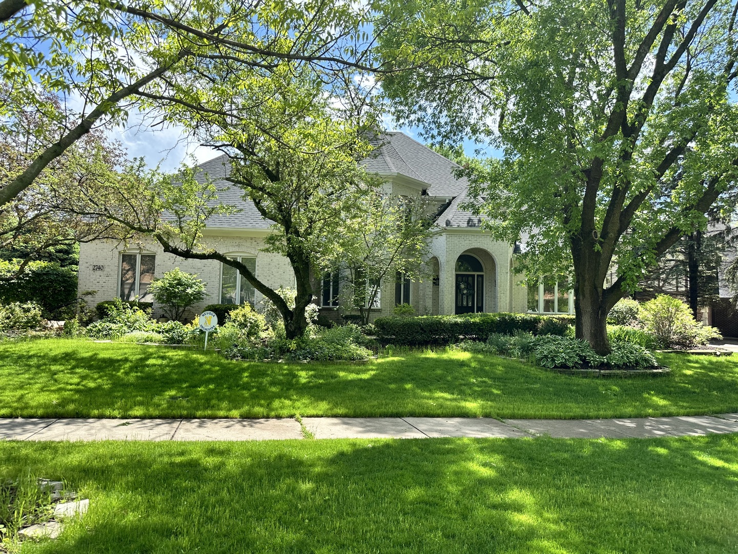a white house with a big yard and large trees