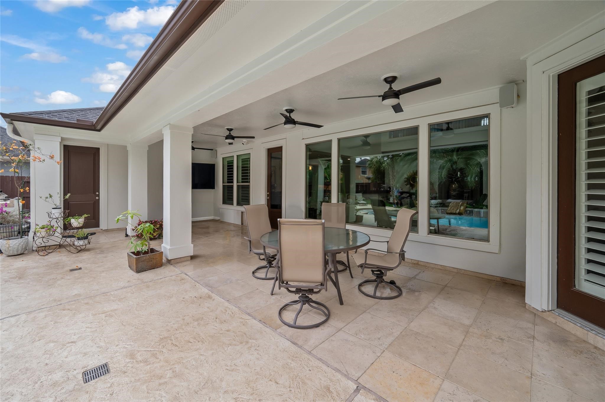 2127 Thicket Ridge Lane Houston, TX 77077 - Photo 36 of 50 Covered patio overlooking backyard and pool. Note the large glass windows and four matching ceiling fans. This view also shows the solid door which leads to the pool bath and opposite door which leads to the primary bedroom.