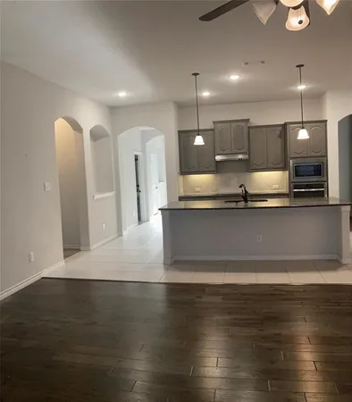 a view of a kitchen with kitchen island a sink wooden floor and a counter top space