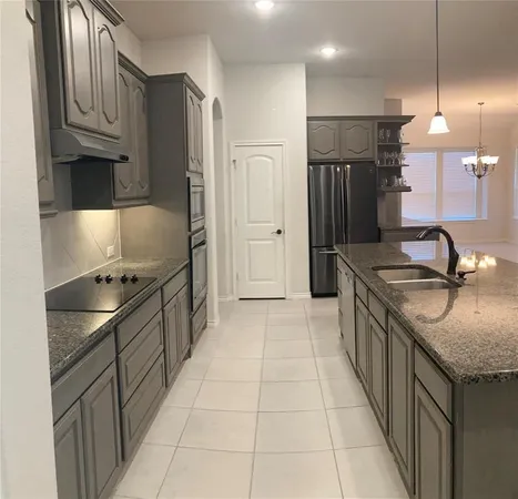 a kitchen with granite countertop a sink stove and refrigerator