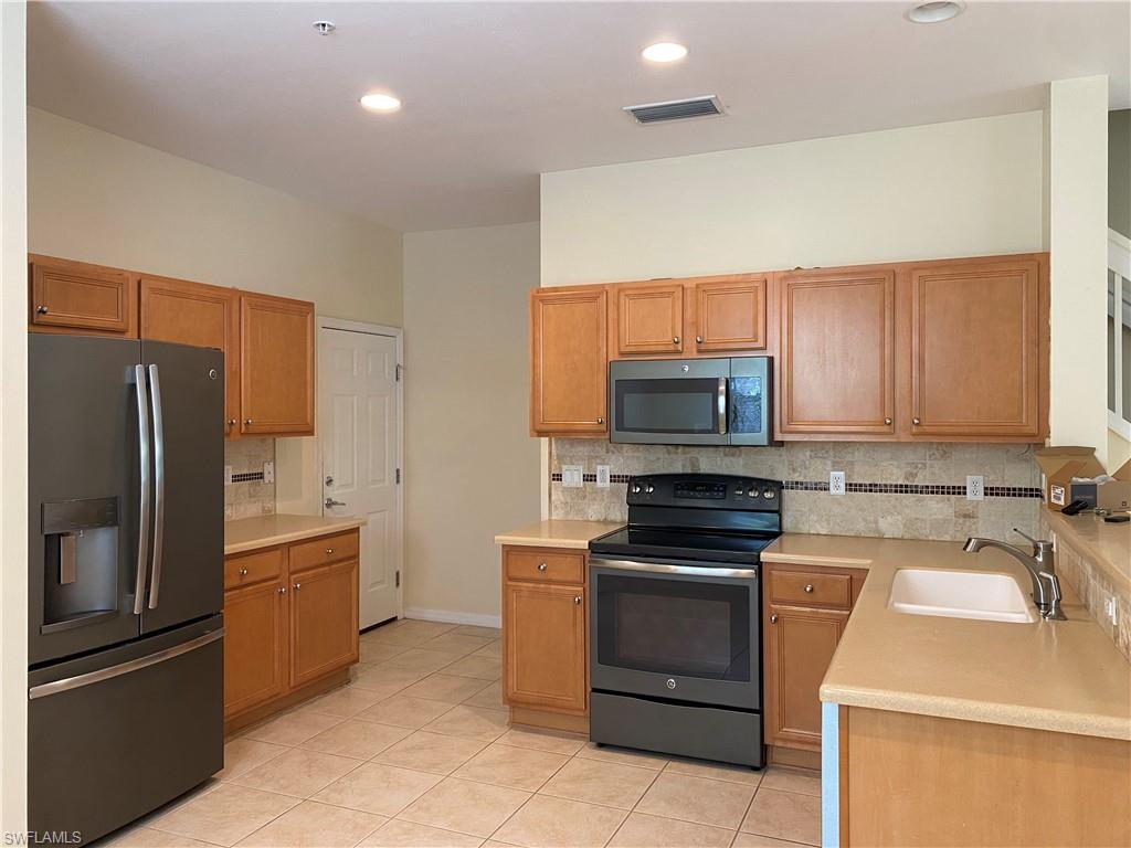 16162 Ravina Way, Unit 65 Naples, FL 34110 - Photo 4 of 12 a kitchen with a refrigerator stove and microwave