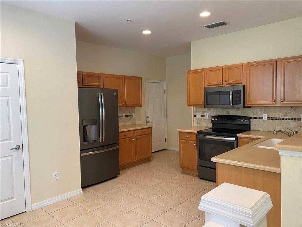 16162 Ravina Way, Unit 65 Naples, FL 34110 - Photo 5 of 12 a kitchen with a refrigerator stove and microwave