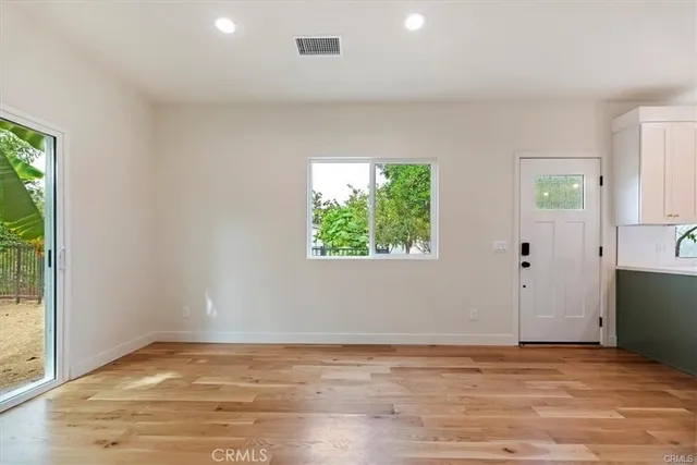 a view of an empty room with wooden floor and a window