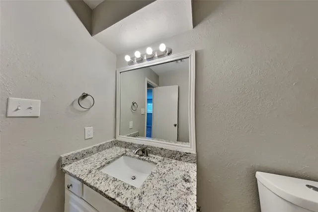 a bathroom with a granite countertop sink a mirror and a vanity