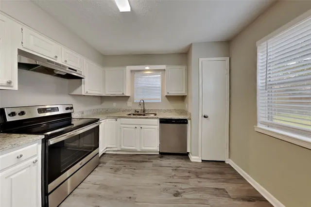 a kitchen with stainless steel appliances granite countertop a sink a stove and a refrigerator