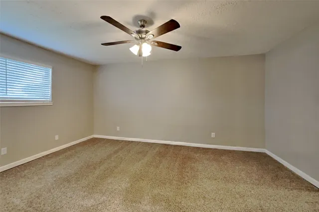 an empty room with a chandelier fan and windows