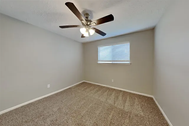 an empty room with a window and a fan