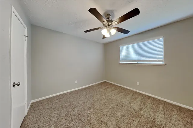 an empty room with a window and a fan