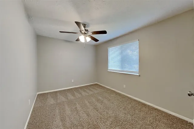 an empty room with a window and a ceiling fan