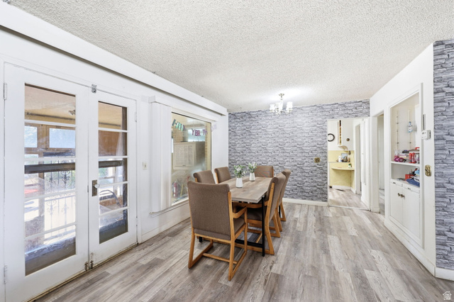 5480 South 2000th Street West Roy, UT 84067 - Photo 16 of 36 Dining area featuring light wood-finish flooring, a decorative stone-patterned accent wall, and a multi-light chandelier