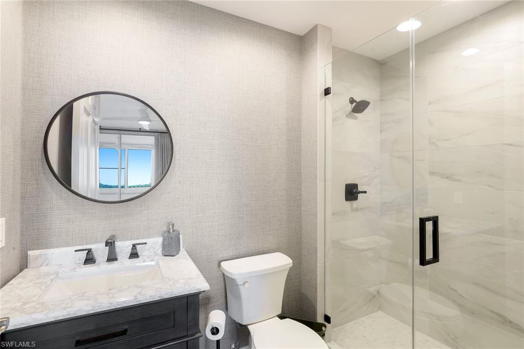 295 Grande Way, Unit 404 Naples, FL 34110 - Photo 14 of 27 a bathroom with a toilet a sink and a mirror
