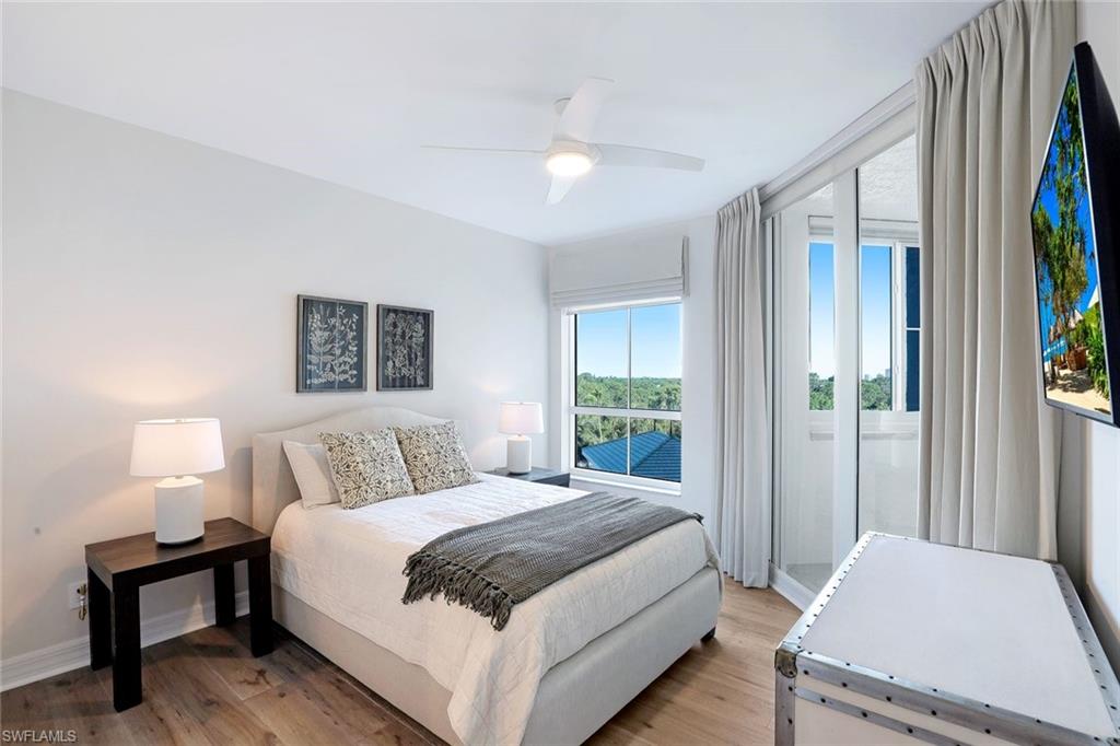 295 Grande Way, Unit 404 Naples, FL 34110 - Photo 15 of 27 a bedroom with a bed lamp and a large window