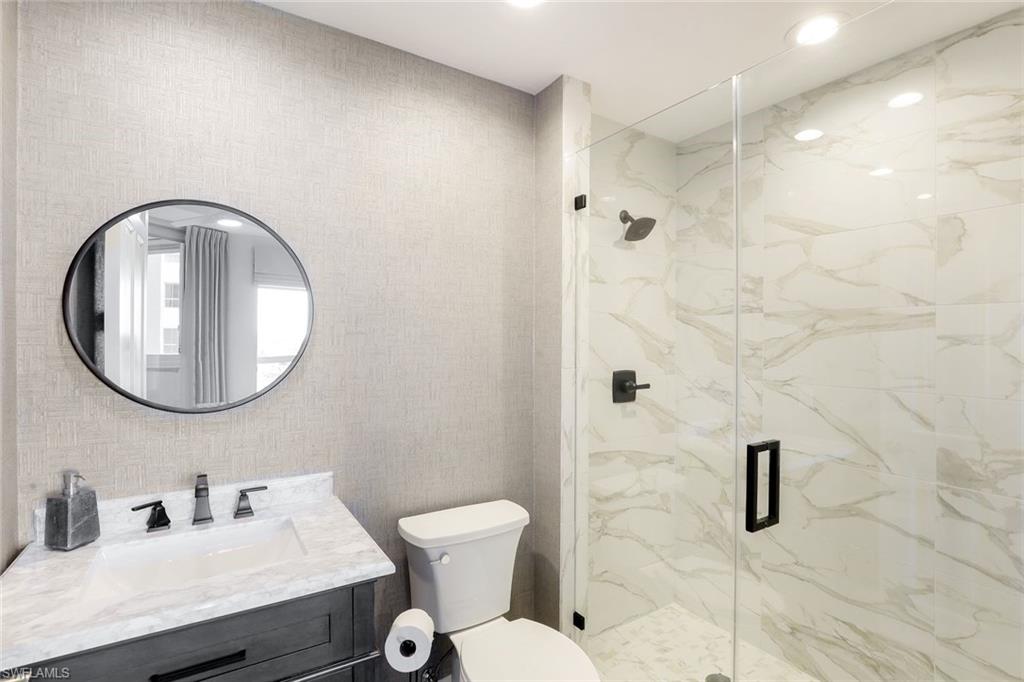295 Grande Way, Unit 404 Naples, FL 34110 - Photo 17 of 27 a bathroom with a toilet sink and mirror