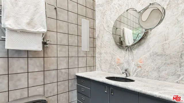 a bathroom with a granite countertop sink a mirror and shower