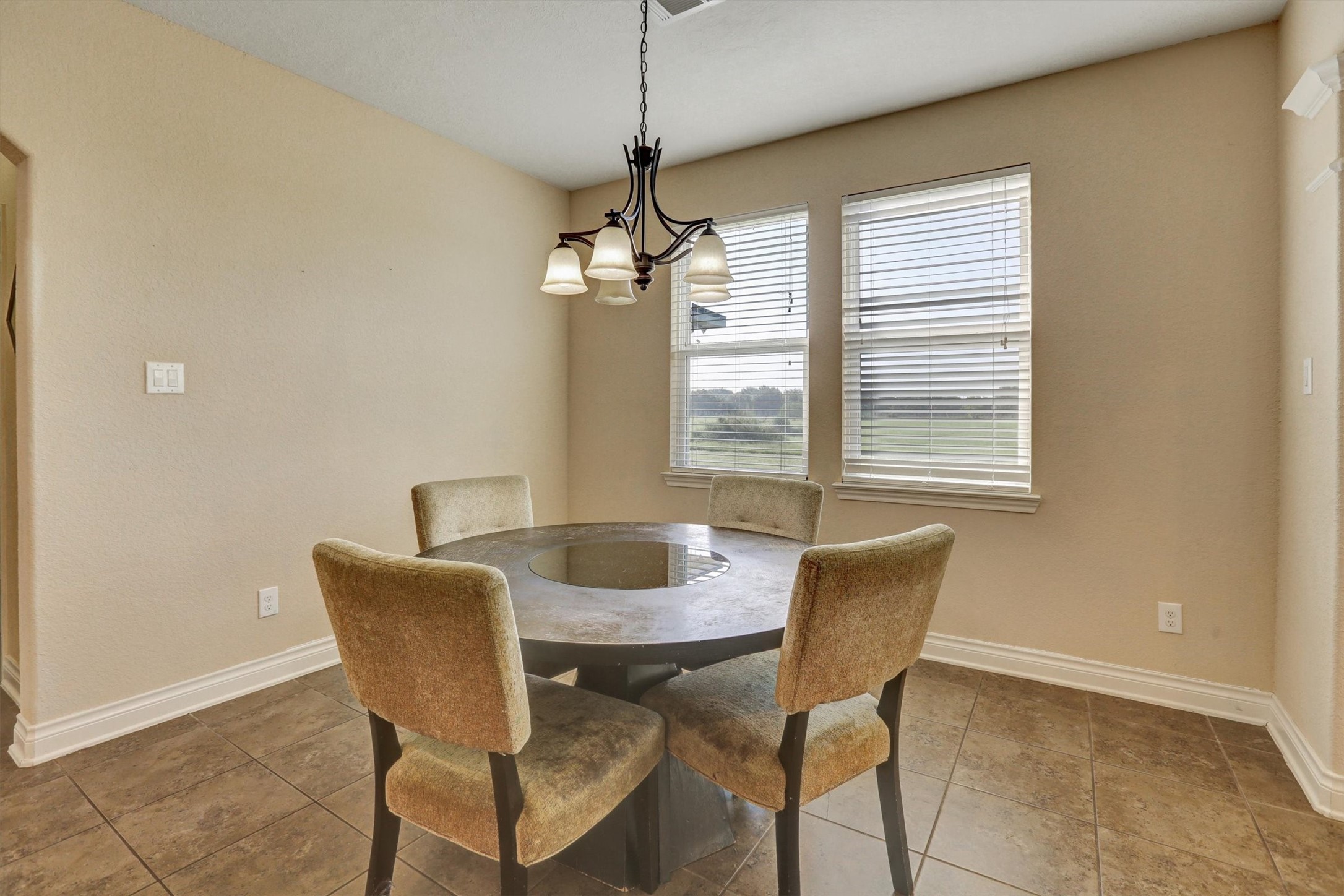 8131 Brinkmeyer Road Needville, TX 77461 - Photo 31 of 49 Cozy dining area with ample natural light from dual windows, featuring a modern round table and elegant overhead lighting.