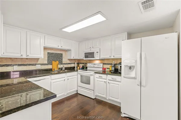 a kitchen with granite countertop white cabinets and white appliances