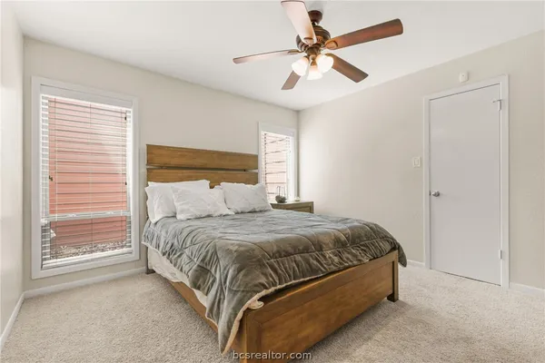 a bedroom with a bed ceiling fan and a window