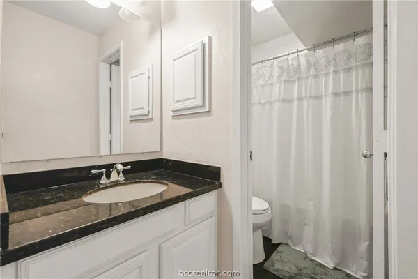 a bathroom with a granite countertop sink and a mirror