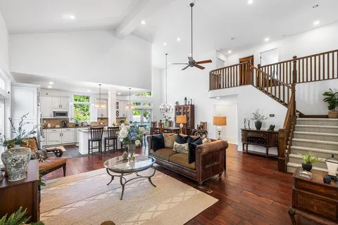 a living room with furniture kitchen view and a wooden floor