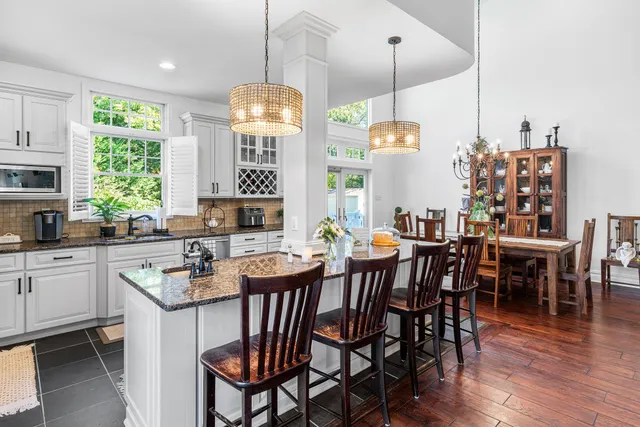a view of a dining room and livingroom with furniture wooden floor a chandelier