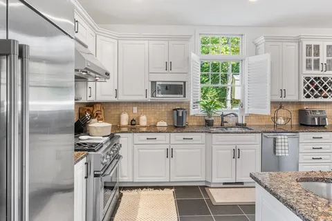 a kitchen with granite countertop a sink stainless steel appliances and cabinets