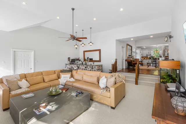 a living room with furniture kitchen view and a chandelier