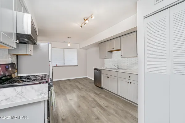 a kitchen with granite countertop a sink cabinets and stainless steel appliances