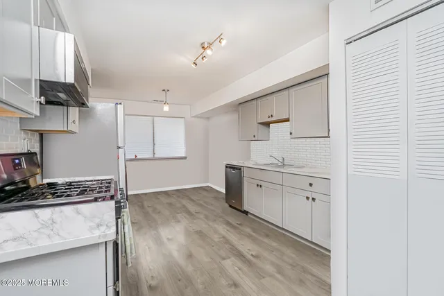 a kitchen with granite countertop a sink cabinets and stainless steel appliances