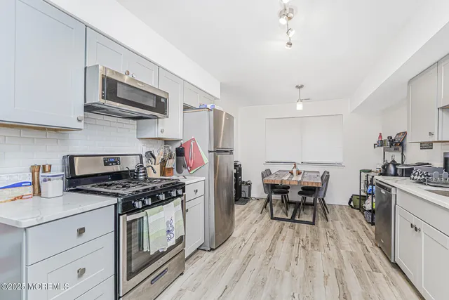 a kitchen with stainless steel appliances a kitchen island hardwood floor sink stove dining table and chairs