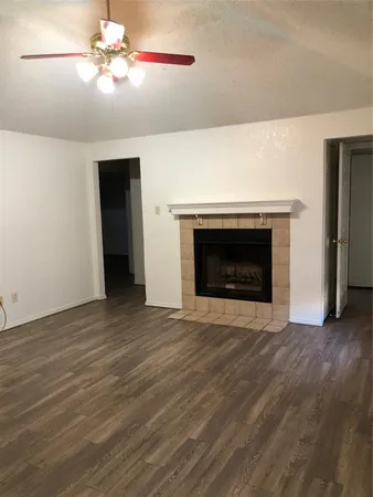 a view of an empty room with wooden floor fireplace and a window