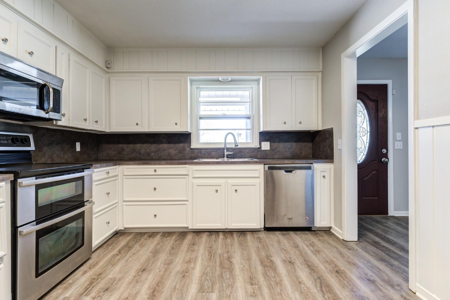 4409 49th Street Lubbock, TX 79414 - Photo 13 of 49 a kitchen with granite countertop white cabinets stainless steel appliances and a sink