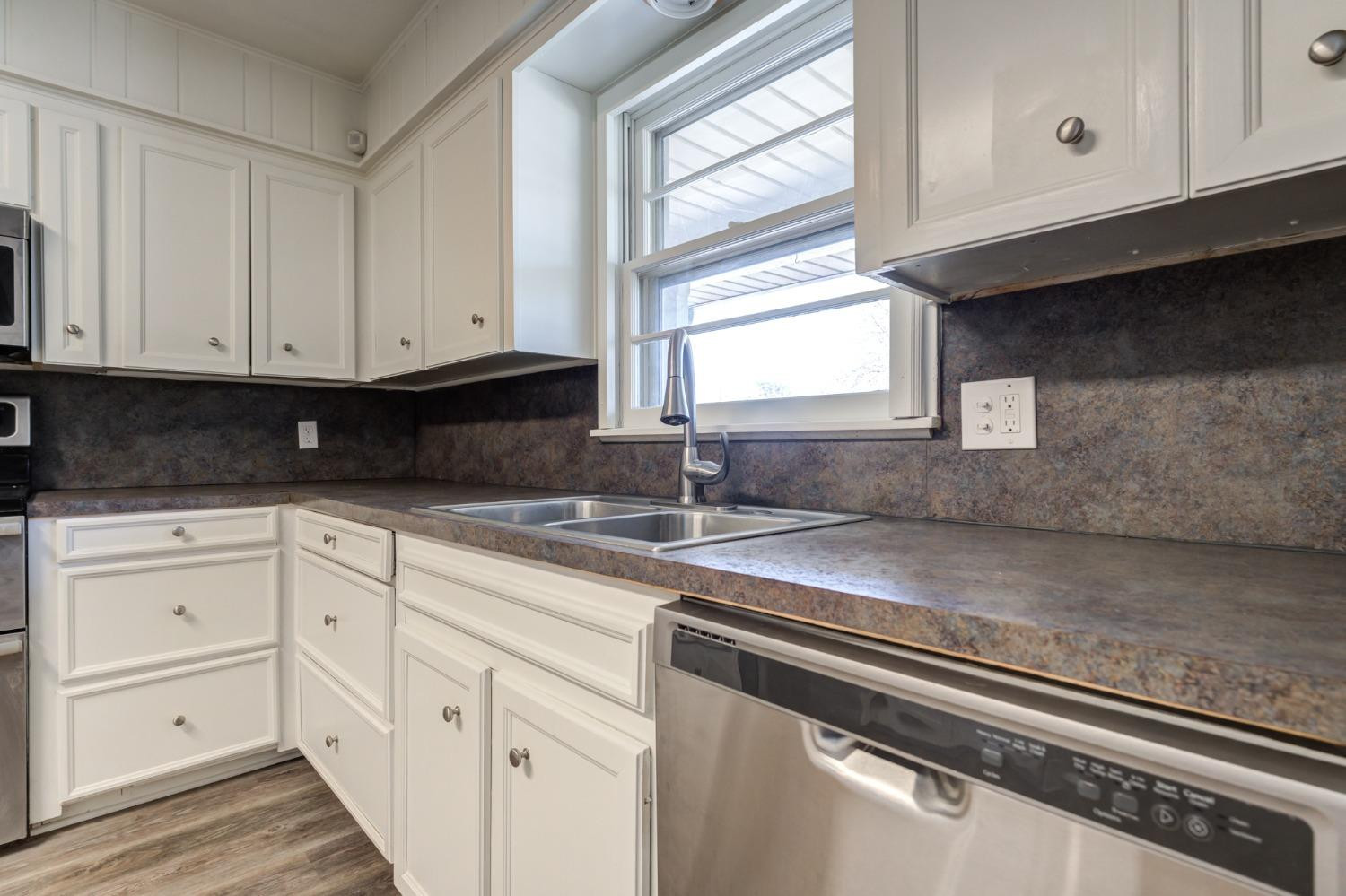 4409 49th Street Lubbock, TX 79414 - Photo 10 of 49 a kitchen with granite countertop white cabinets and white appliances