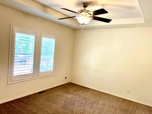 an empty room with windows and fan