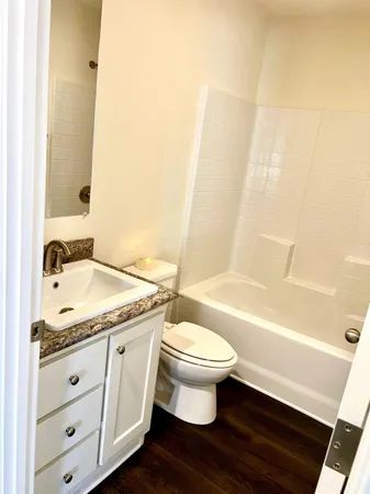 a bathroom with a granite countertop sink toilet a mirror and bathtub