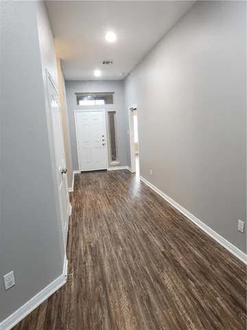 a view of an empty room with wooden floor and closet