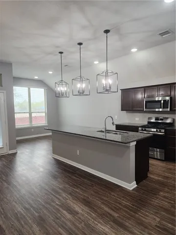 a kitchen with stainless steel appliances granite countertop a sink a stove a microwave and wooden floor