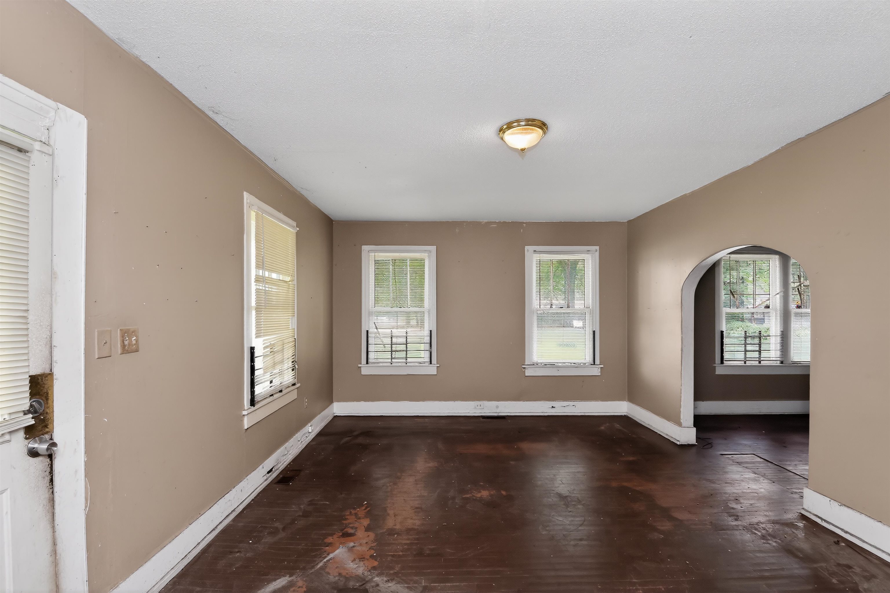 810 Hale Road Memphis, TN 38116 - Photo 12 of 30 Spacious room with multiple windows, an arched doorway, and a ceiling-mounted light fixture